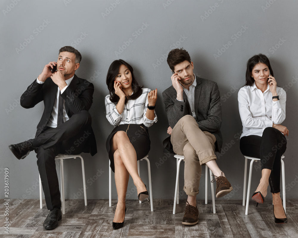 Obraz premium interracial business people talking on smartphones while waiting for job interview