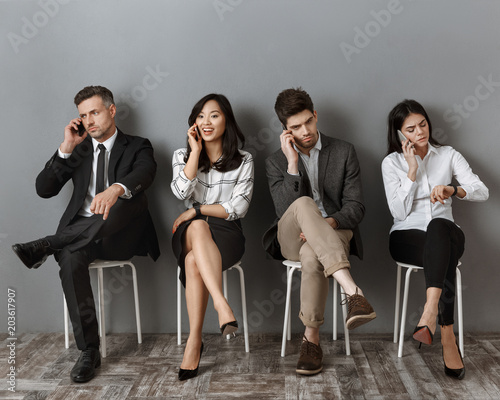 interracial business people talking on smartphones while waiting for job interview