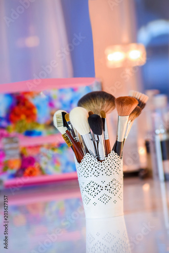 a set of brushes for make-up at the white table on color blurred background