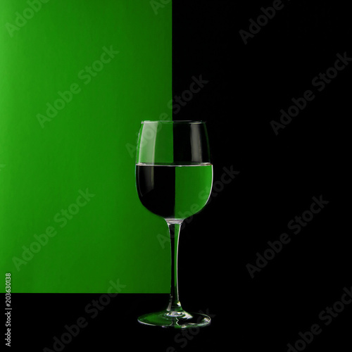 Glass wine glass on a black and green background. Mirror image. Different background colors