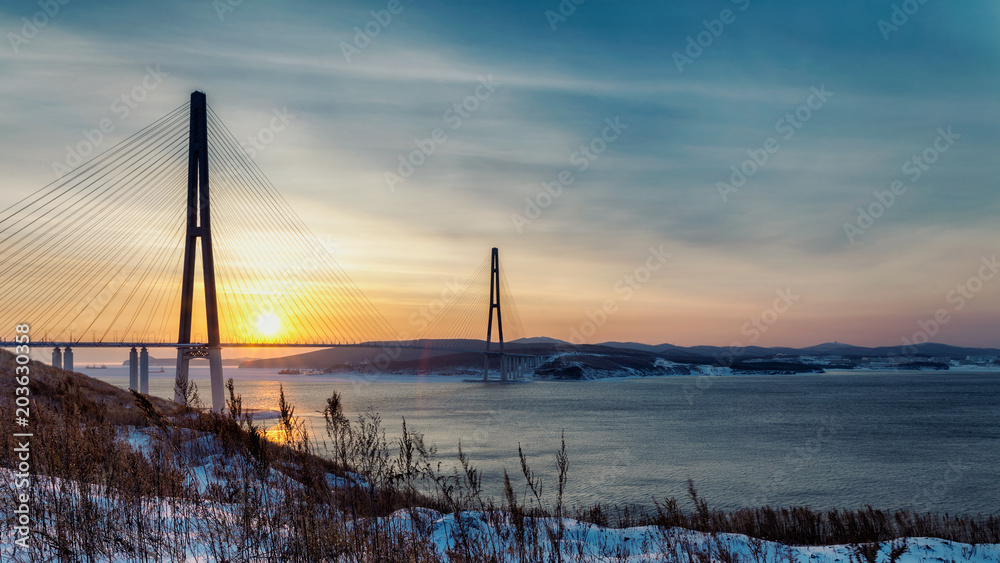 Winter sunset view with fresh snow and long cable-stayed bridge in Vladivostok, Russia
