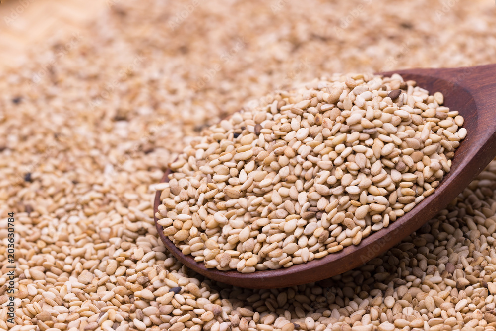 white sesame in wooden spoon on sesame background. white sesame in wooden spoon on sesame background.