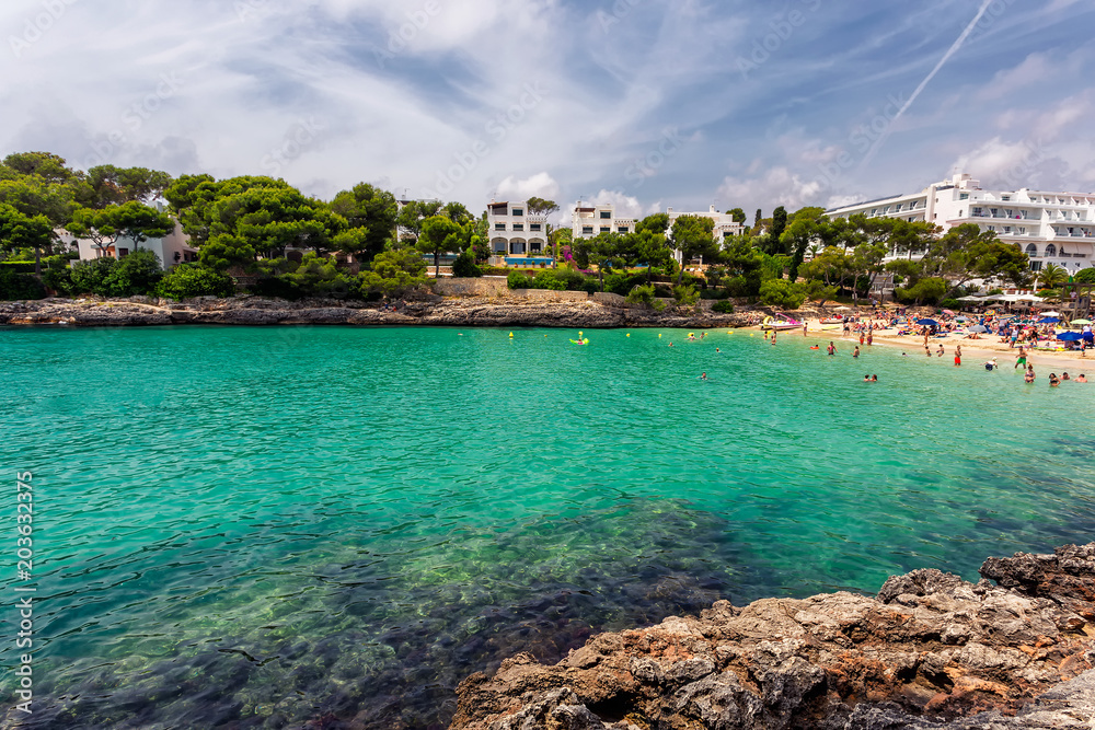 Cala Gran beach with turquoise water crowded with tourists in Mallorca, Spain