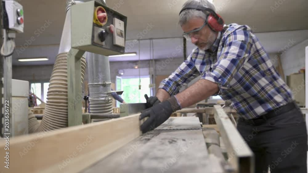 Wood worker cutting piece of wood with machine Wood worker cutting piece of wood with machine
