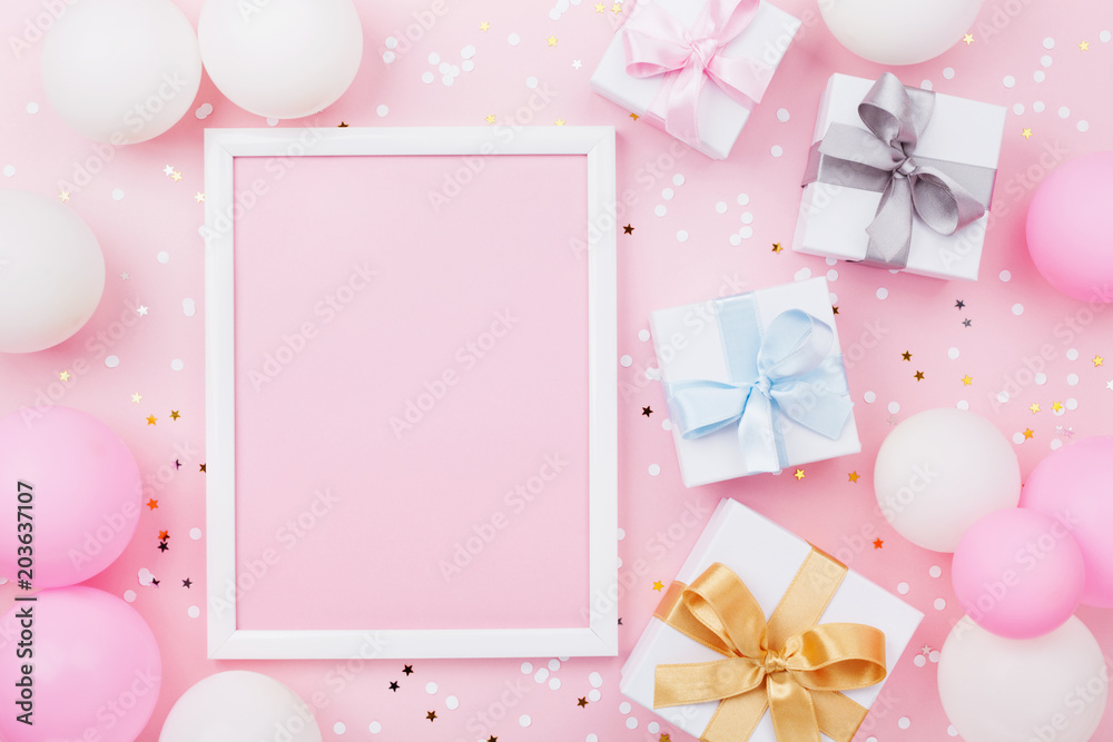 Birthday or holiday mockup with frame, gift box, pastel balloons and confetti on pink table top view. Flat lay composition.
