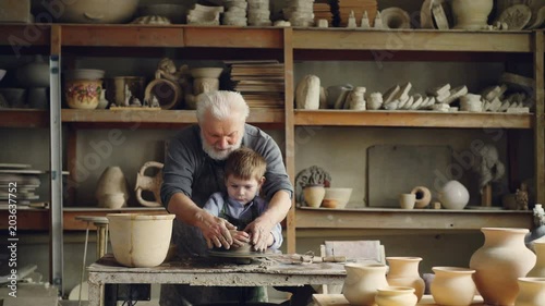 Wallpaper Mural Loving grandfather professional potter is teaching his small grandchild to mold clay on potter's wheel. Little boy is laughing and enjoying new hobby. Torontodigital.ca