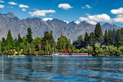 Fototapeta Naklejka Na Ścianę i Meble -  Steam-powered ship on lake Wakatipu surrounded by coniferous forest and mountains in Queenstown, New Zealand