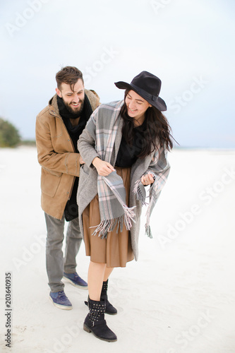 Happy girl and man wearing coats and scarfs standing in winter snow background. Concept of happy couple and positive emotions. photo