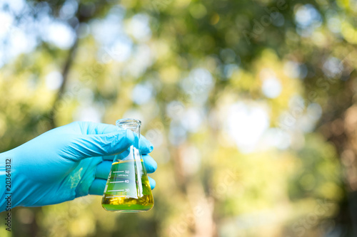 Hand holding chemistry science flask,Erlenmeyer flask over green bokeh background,concept for alternative medicine