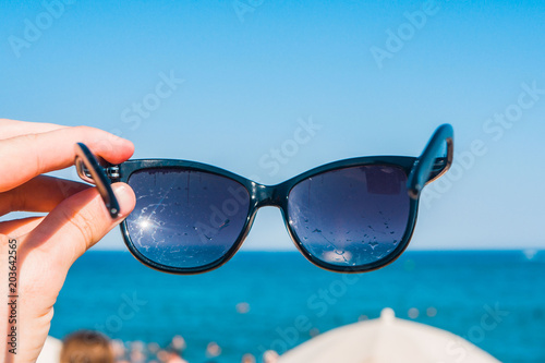 Sunglasses in a hand on the beach, bright summer day