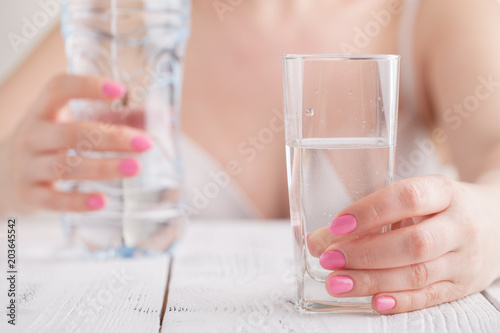 Female hand holding a glass of clean water, close-up.