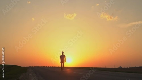 The man is walking in the sunset.