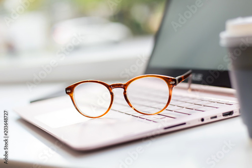 Desk with laptop, eye glasses, and a cup of coffee. Concept of business