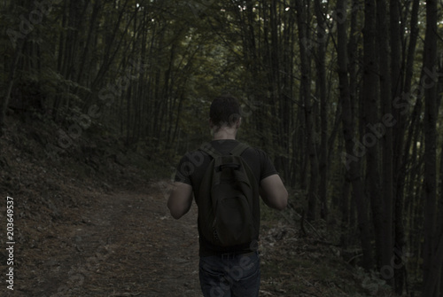 Young man with a backpack exploring a dark forest
