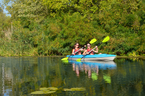 Family kayaking, mother and daughter paddling in kayak on river canoe tour having fun, active autumn weekend and vacation with children, fitness concept 