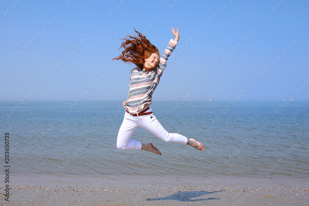 Wunschmotiv: Hübsche rothaarige Frau springt an einem Strand in die Luft Meer im Hintergrund #203650