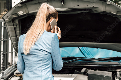 Woman calling for assistance with broken down car engine on street © Art_Photo