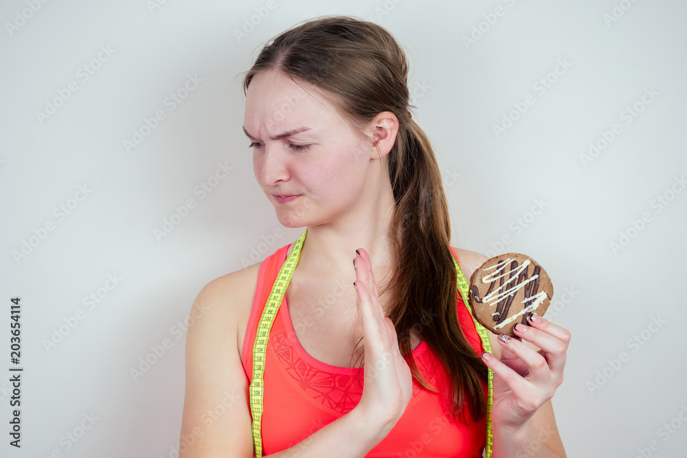 Portrait of a young and beautiful teenage girl holding a biscuit and measuring tape Portrait of a young and beautiful teenage girl holding a biscuit and measuring tape