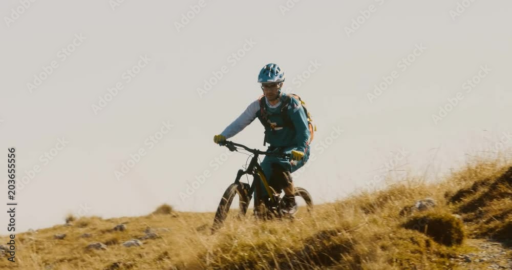 Front view of mountain biker riding down hill against a blue sky. Front view of mountain biker riding down hill against a blue sky.