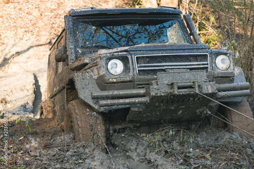 SUV is pulled out from puddle of mud by car winch. photo