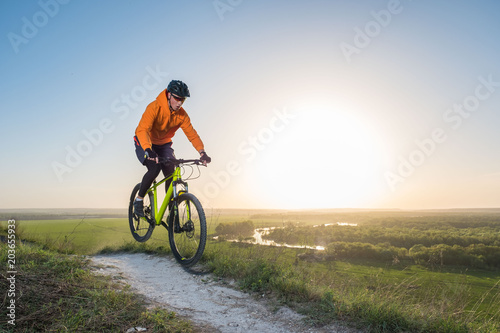 A cyclist in an orange hoodie rides a bike along a mountain path. The concept of extreme sports. Training in the mountains.