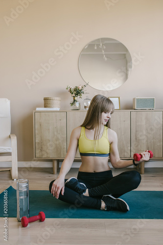 Fitness girl in at stylish home raises the bar up at the floor. She wears yellow sporing t-shirt photo