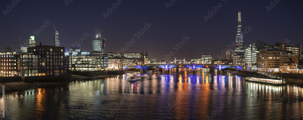 Fototapeta premium Beautiful London City skyline landscape at night with glowing city lights and iconic landmark buldings and locations