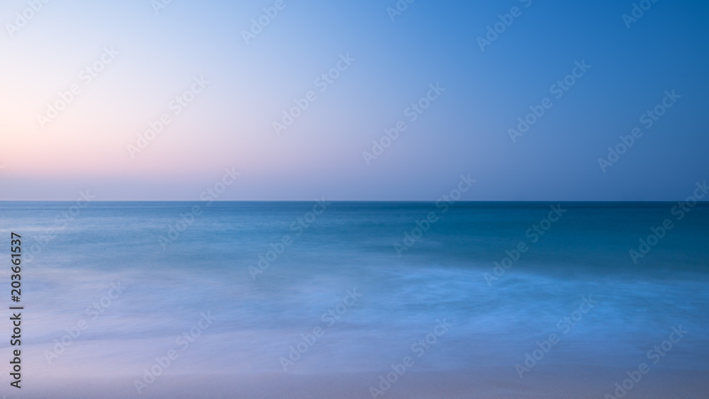 Stunning vibrantl sunrise landscape image of calm sea looking out from Porthcurno beach on South Cornwall coast in England