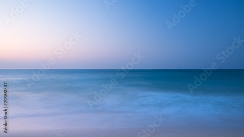 Stunning vibrantl sunrise landscape image of calm sea looking out from Porthcurno beach on South Cornwall coast in England