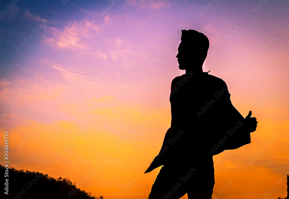 The silhouette of a man, his arms muscles show strong on the background of the sunset. By Phawat