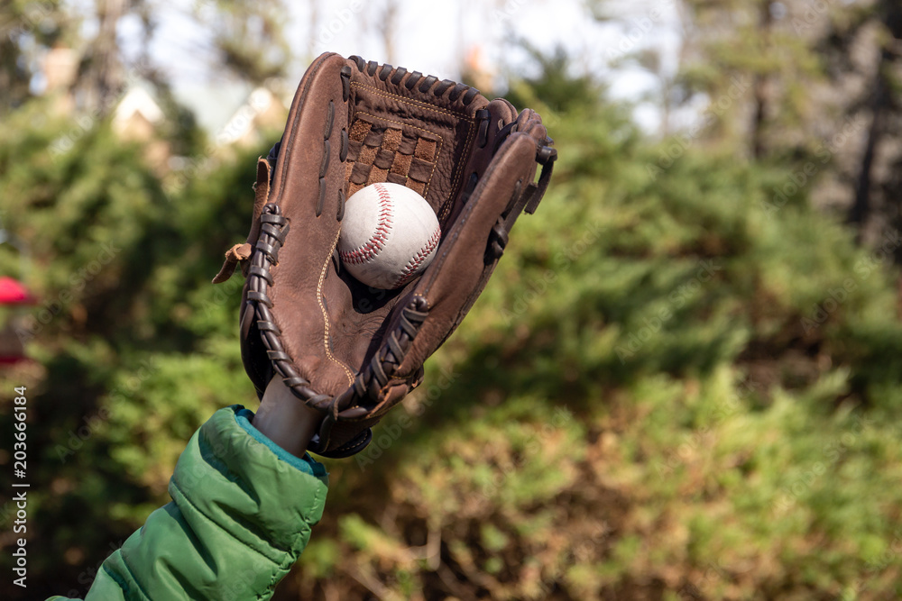 Naklejka premium Children hand with baseglove holding baseball ball