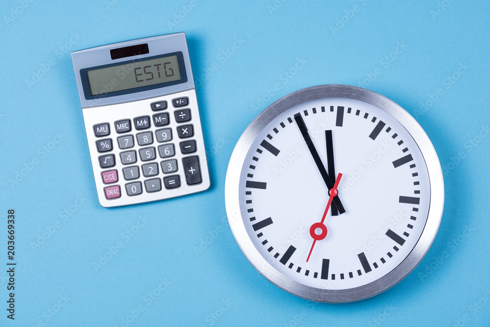 Taschenrechner mit dem Wort ESTG zur Einkommenssteuer und einer Uhr Taschenrechner mit dem Wort ESTG zur Einkommenssteuer und einer Uhr