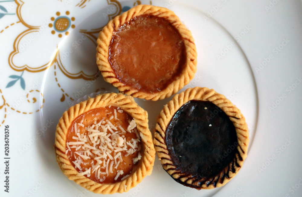 Custard tarts from Bali, Indonesia. Known as pie susu. Topping with chocolate, cheese and original. Made from flour, margarine, egg, sugar and milk.