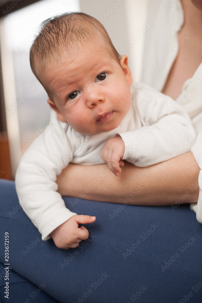 3 months old baby boy rests on mothers legs 3 months old baby boy rests on mothers legs