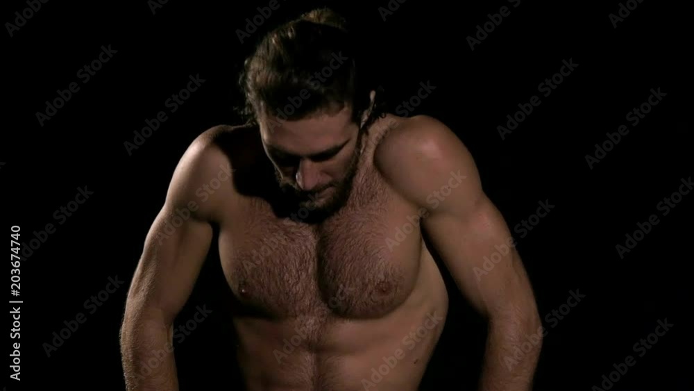 Very fit man doing warm up before exercise with black background. Sitting down and relaxing. Slow motion. Very fit man doing warm up before exercise with black background. Sitting down and relaxing. Slow motion.