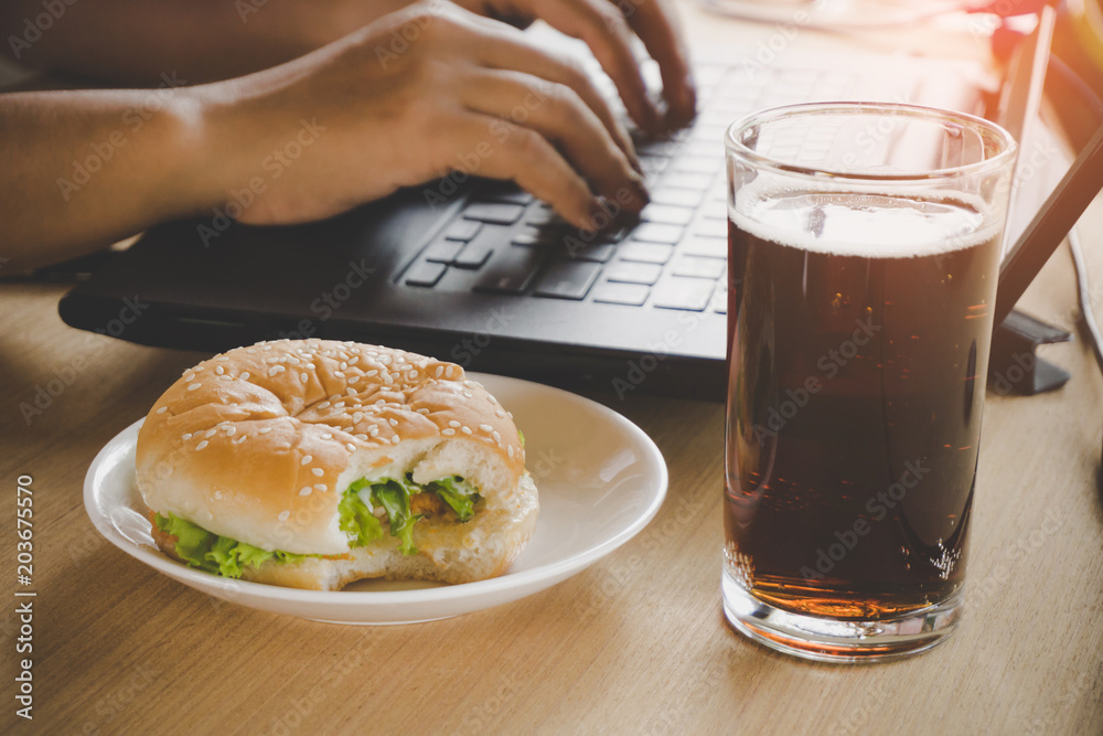 business woman eating junk food burger and cold drink while working on computer laptop at office desk, unhealthy lifestyle concept business woman eating junk food burger and cold drink while working on computer laptop at office desk, unhealthy lifestyle concept