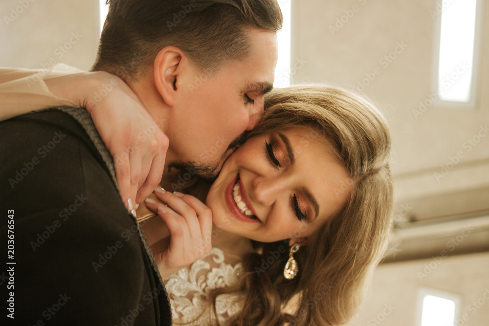 A young couple are basking, a man is kissing a girl. Emotions and smiles, enjoying the kiss.