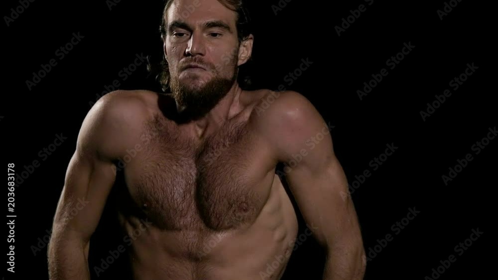 Very fit man doing warm up before exercise with black background. Sitting down and relaxing. Slow motion. Very fit man doing warm up before exercise with black background. Sitting down and relaxing. Slow motion.