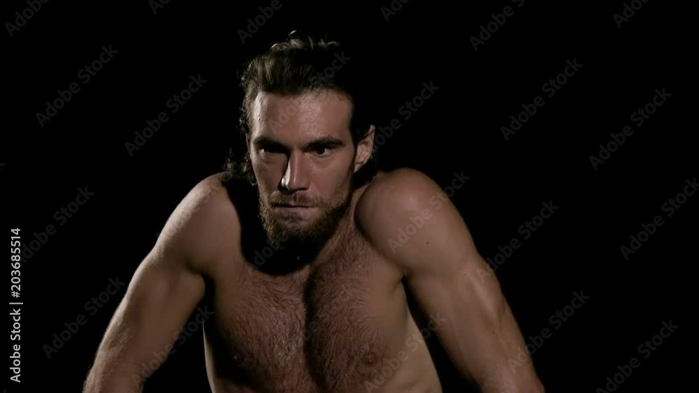 Very fit man doing warm up before exercise with black background. Sitting down and relaxing. Slow motion. Very fit man doing warm up before exercise with black background. Sitting down and relaxing. Slow motion.