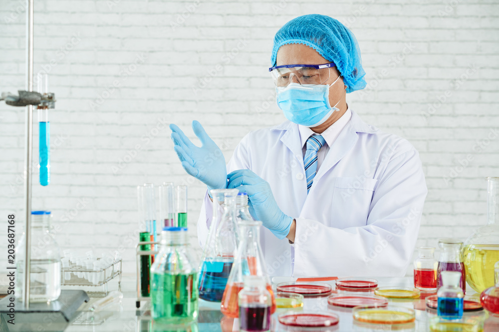Asian Scientist Adjusting Rubber Gloves Asian Scientist Adjusting Rubber Gloves