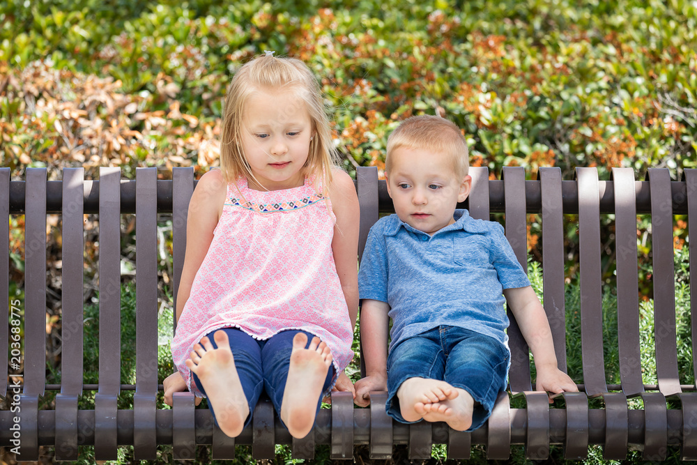 Young Sister and Brother Having Fun On The Bench At The Park Young Sister and Brother Having Fun On The Bench At The Park