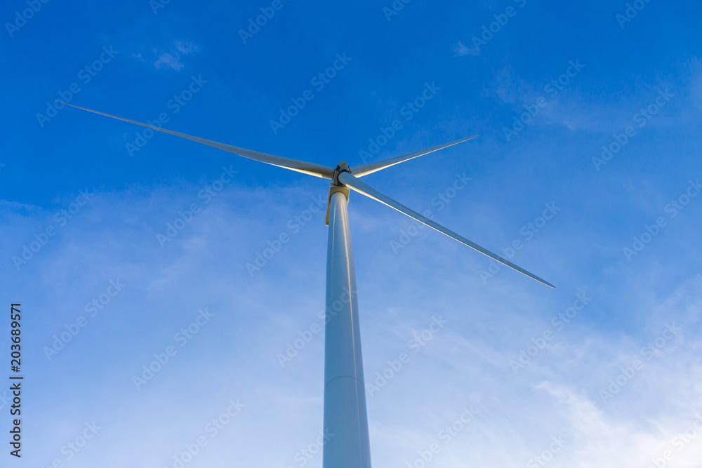 White wind turbine for alternative energy in day with blue sky background, electric clean power concept White wind turbine for alternative energy in day with blue sky background, electric clean power concept