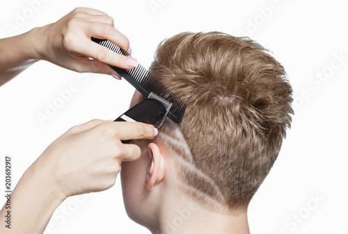 A hairdresser does a haircut for a young man in a barbershop.