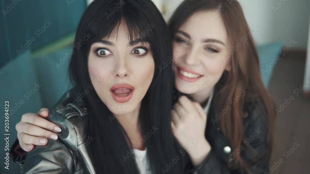 girlfriends do selfie on mobile phone cameras while sitting in a cafe. two attractive girls take pictures on the camera of the smartphone and fool around girlfriends do selfie on mobile phone cameras while sitting in a cafe. two attractive girls take pictures on the camera of the smartphone and fool around