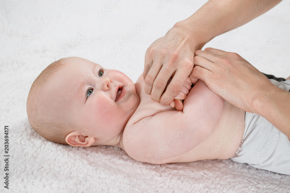 Female doctor doing massage and gymnastic baby on a light background Female doctor doing massage and gymnastic baby on a light background