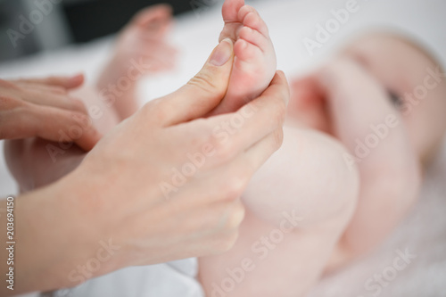 Mother does a foot massage to a newborn baby. mother's care. healthy lifestyle. Face is blurred in background. Close-up