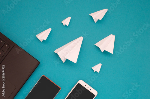 White paper planes and gadgets on a blue background. Visual communication scheme through messenger Telegram