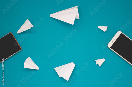 White paper planes and gadgets on a blue background. Visual communication scheme through messenger Telegram