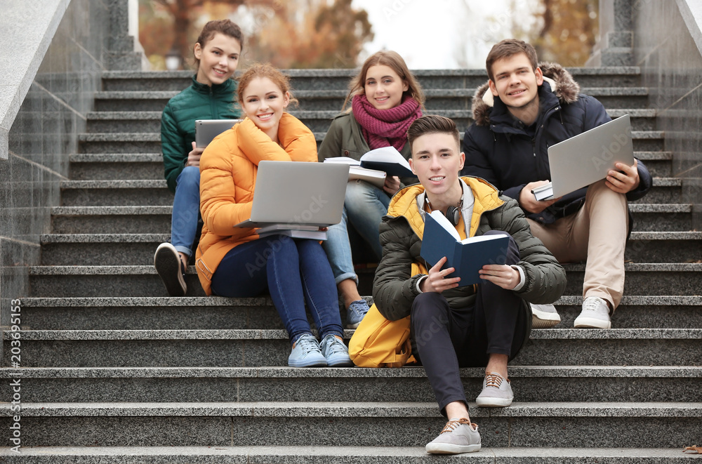 Fototapeta premium Group of teenagers studying on stairs outdoors