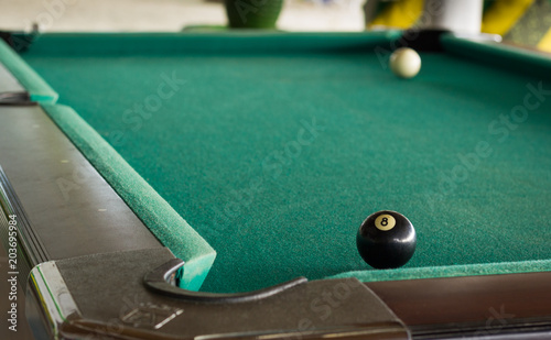 Obraz na plátně White cue ball and black ball on opposite sides of pool table with green baize